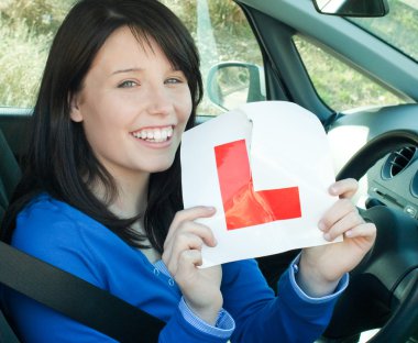 Happy teen girl sitting in her car tearing a L-sign clipart