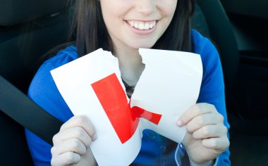 Charming teen girl sitting in her car tearing a L-sign clipart