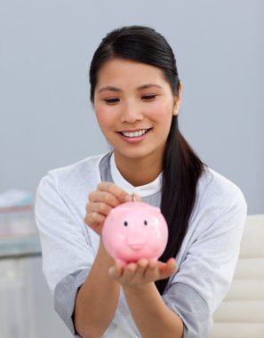 Asserive businesswoman saving money in a piggybank clipart