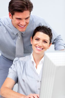 Smiling business woman and her colleage working at a computer clipart