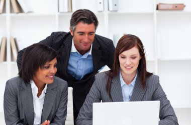 Charming businesswomen and their colleague working at a laptop clipart