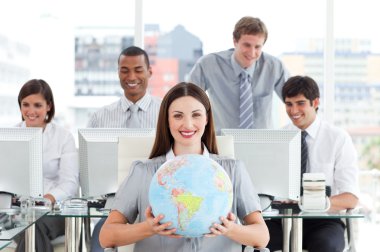 Brunette businesswoman and her team showing a terrestrial globe clipart