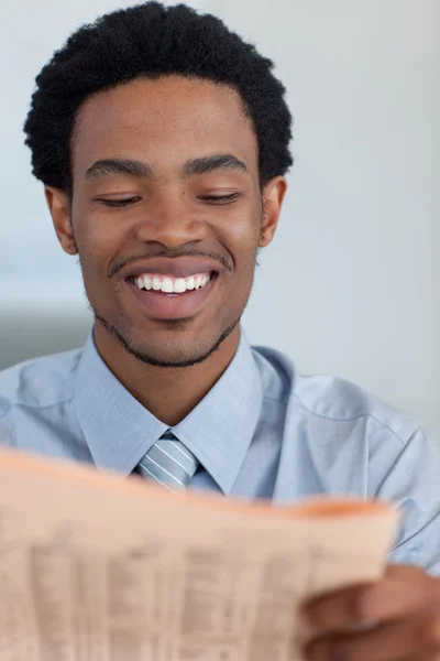 Empresário afro-americano sorrindo lendo um jornal — Fotografia de Stock