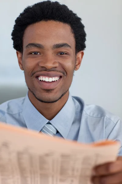 Uomo d'affari afro-americano con un giornale che sorride alla telecamera — Foto Stock
