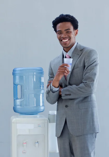 Бизнесмен пьет воду из холодильника в офисе — стоковое фото