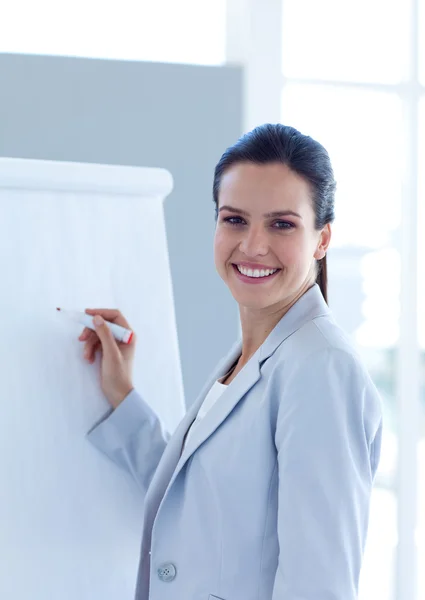 Empresária sorridente escrevendo em um quadro branco — Fotografia de Stock