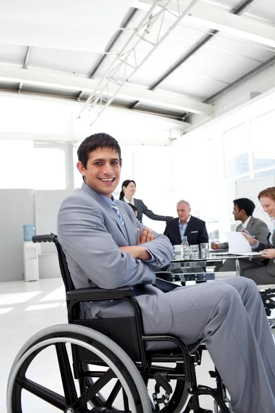Empresário atraente sentado em uma cadeira de rodas com braços dobrados — Fotografia de Stock