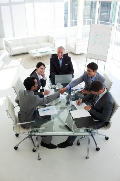 Бізнесмени тремтять руками, сидячи навколо конференц-столу — стокове фото