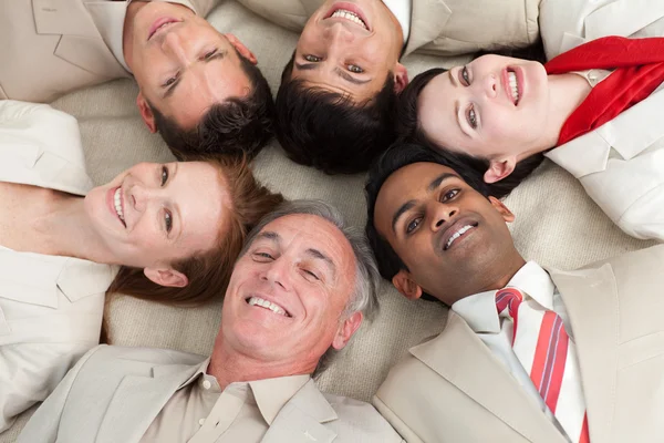 Бизнес-команда лежит на полу с головами вместе — стоковое фото
