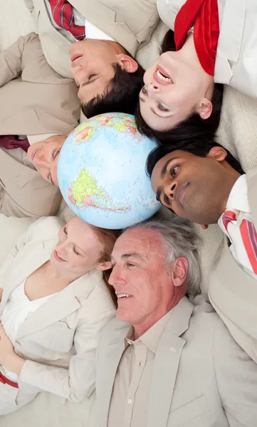 Multietniska verksamhet team liggande på golvet runt en terrestri — Stockfoto