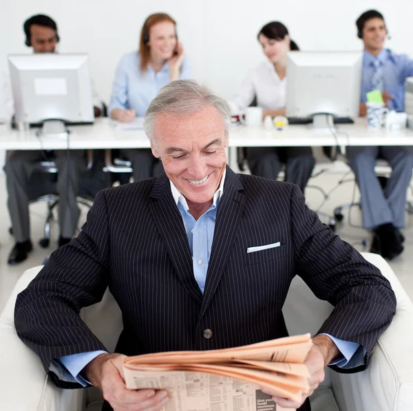 Empresário sorridente lendo um jornal — Fotografia de Stock