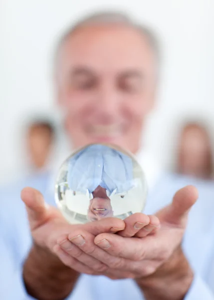 Homme d'affaires senior tenant une boule de cristal — Photo