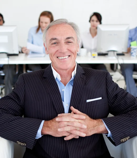 Smiling senior manager with his team in the background — Stock Photo, Image