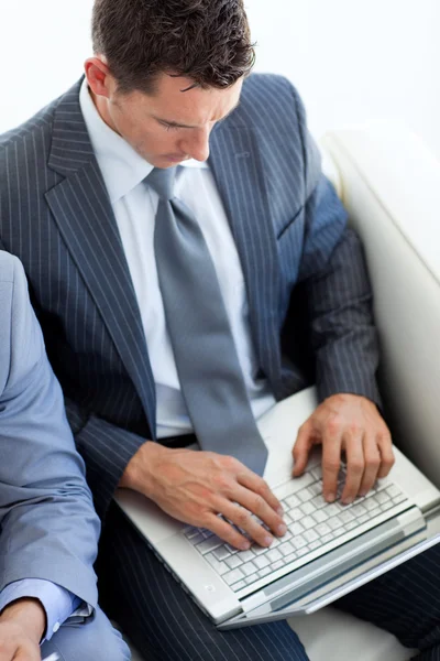 Aantrekkelijke zakenman met behulp van een laptop tijdens het wachten voor een baan in — Stockfoto