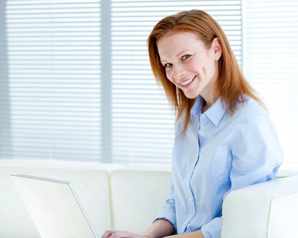 Bir dizüstü bilgisayar üzerinde çalışan iş kadın gülümsüyor — Stok fotoğraf