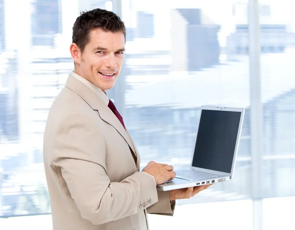 Positive businessman using a laptop standing — Stock Photo, Image
