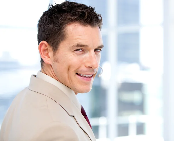Hombre de negocios sonriente con auriculares en pie —  Fotos de Stock