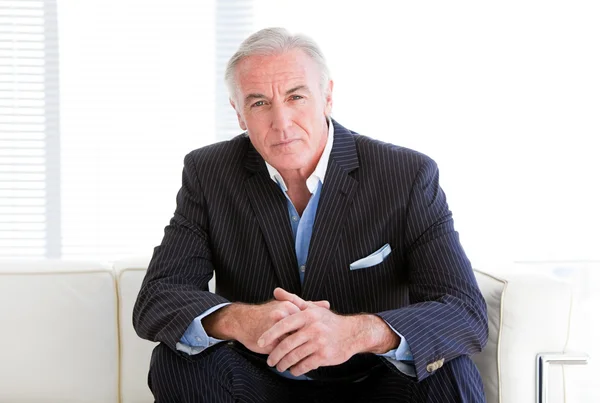 Charismatischer Senior-Geschäftsmann sitzt auf einem Sofa — Stockfoto