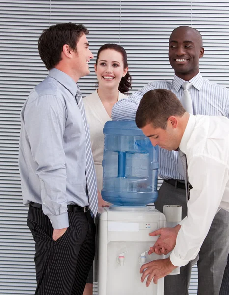 Smiling multi-ethnic business interacting at a watercoole — Stock Photo, Image