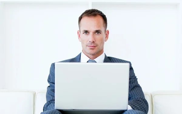 Empresário confiante usando um laptop sentado em um sofá — Fotografia de Stock