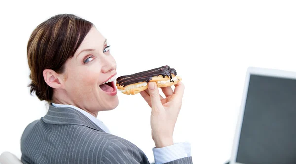 Empresária encantada comendo um eclair de chocolate — Fotografia de Stock