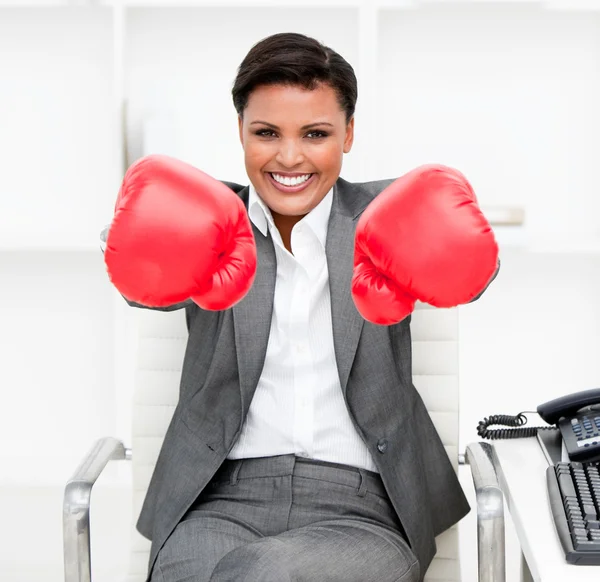 Attractive businesswoman wearing boxing gloves sitting at her de — Stok fotoğraf