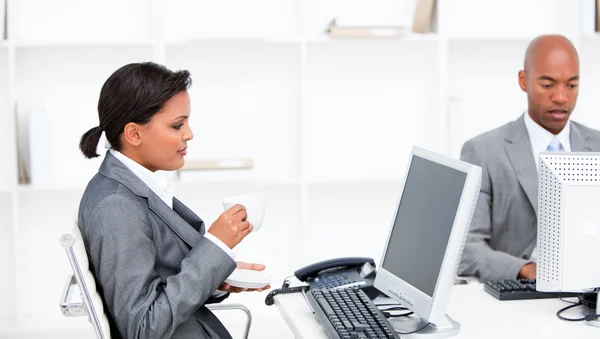 Säker affärskvinna dricka en kaffe medan du arbetar på en comp — Stockfoto