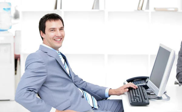 Leende ung affärsman som arbetar på en dator — Stockfoto