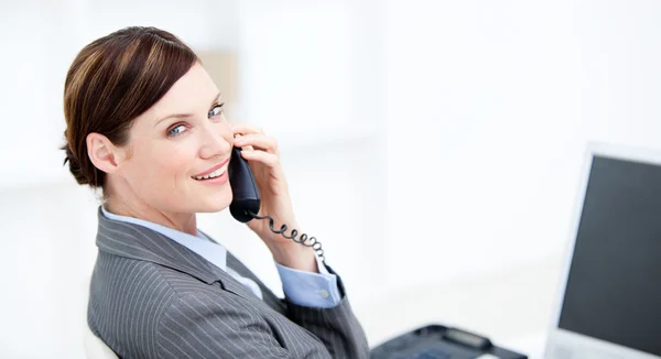 Lächelnde Geschäftsfrau am Telefon sitzt an ihrem Schreibtisch — Stockfoto