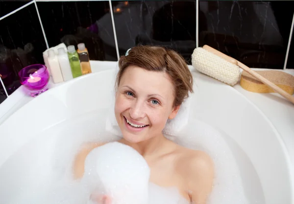 Femme souriante jouant dans un bain moussant — Photo