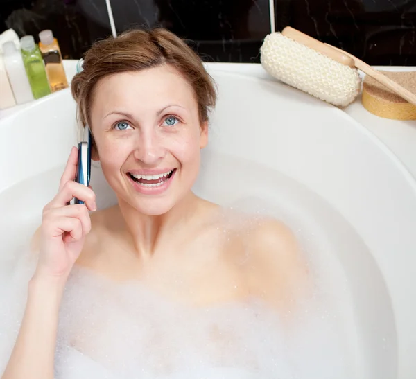 Femme lumineuse parlant au téléphone dans un bain moussant — Photo