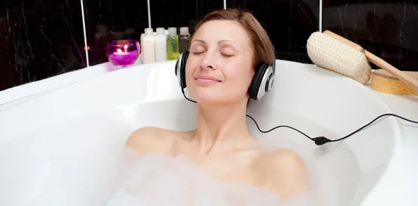Расслабленная женщина слушает музыку в ванне с пеной — стоковое фото