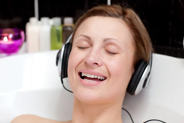 泡風呂で音楽を聴く若い女性の笑みを浮かべてください。 — ストック写真