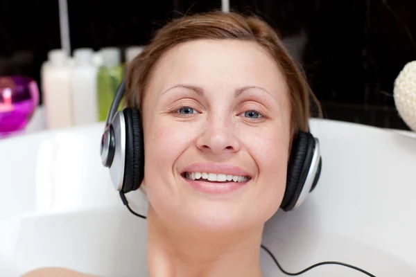Χαρούμενα γυναίκα χρησιμοποιώντας ακουστικά σε ένα αφρόλουτρο — Φωτογραφία Αρχείου