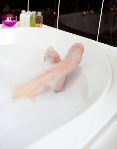 Pies de mujer en un baño de burbujas — Foto de Stock
