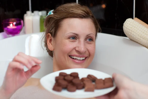 Светлая женщина ест шоколад, принимая ванну — стоковое фото