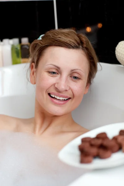 행복 한 여자 목욕 하는 동안 초콜릿을 먹는 — 스톡 사진