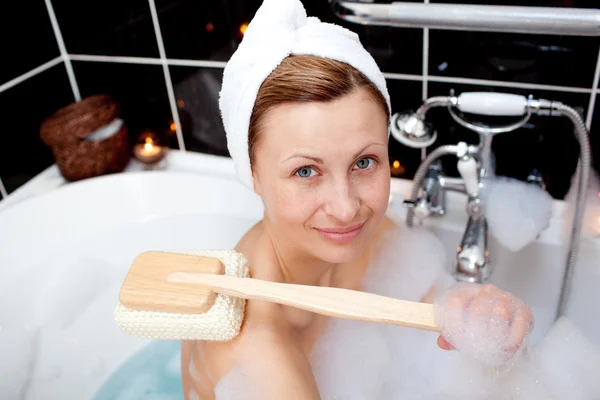 Улыбающаяся белая женщина принимает ванну с пеной — стоковое фото