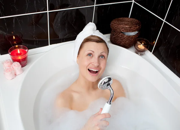 Веселая молодая женщина поет в ванне с пеной — стоковое фото