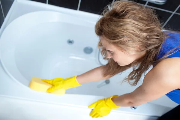 Mujer joven limpiando un baño — Foto de Stock