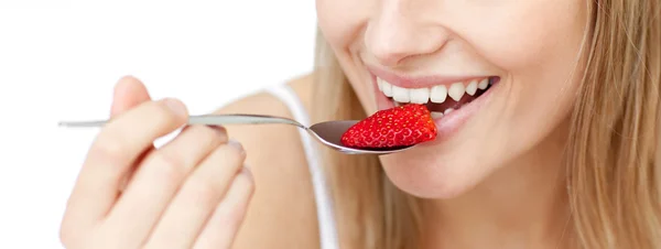 Nahaufnahme einer lächelnden Frau, die eine Erdbeere isst — Stockfoto