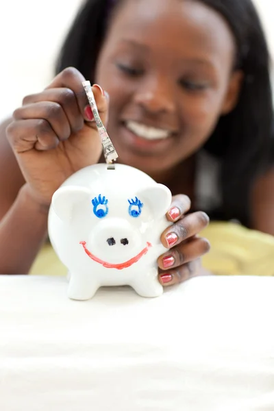 Afro-American tonåring tjej att lägga pengar i en spargris — Stockfoto