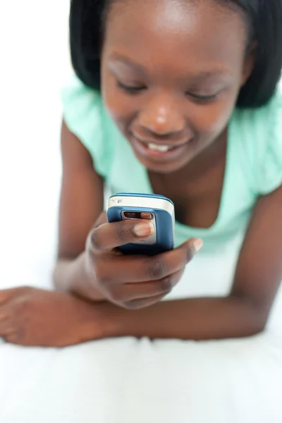 Afro-American dospívající dívka pomocí mobilního telefonu, ležící na posteli — Stock fotografie