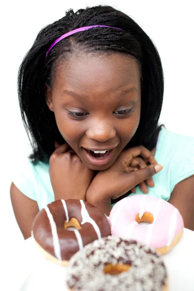 Έκπληκτος νεαρή γυναίκα κοιτάζοντας ντόνατς — Φωτογραφία Αρχείου