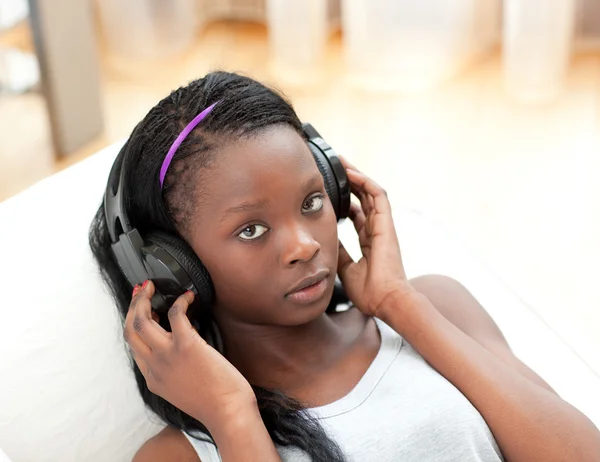 Hermosa mujer escuchando música con auriculares tumbados en un sofá —  Fotos de Stock