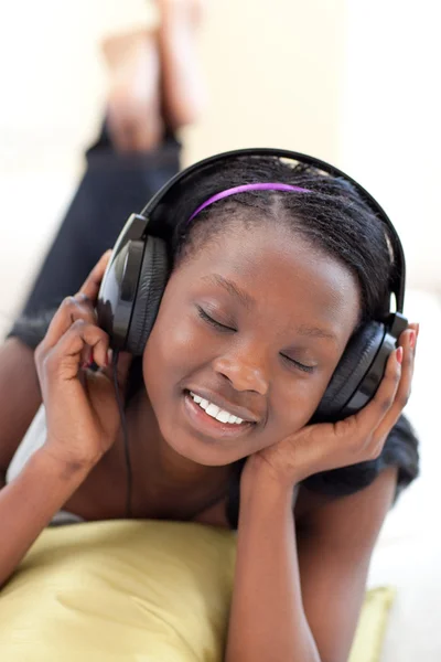 Linda mujer escuchando música con auriculares tumbados en un sofá —  Fotos de Stock