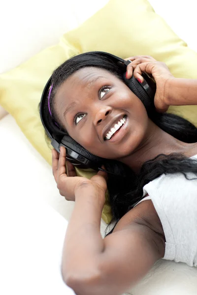 Freudige Frau hört Musik mit Kopfhörern auf dem Sofa liegend — Stockfoto