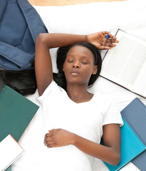 Trött student gör sina läxor liggande på en säng — Stockfoto