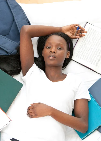 Joven estudiante haciendo sus deberes acostada en una cama — Stockfoto