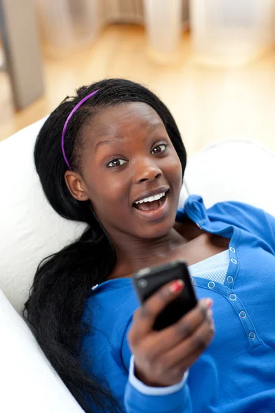 Glad kvinna skicka en text liggande på en soffa — Stockfoto